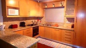 A kitchen with wooden cabinets, a granite countertop, a microwave, a stove, and a sink. - Beach House - Between Porto, Braga and Viana do Castelo (Esposende)
