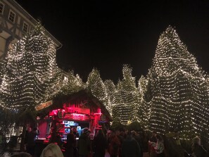 Cena noturna com árvores de Natal iluminadas e um quiosque de comida.