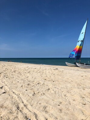 Una playa con un velero y un cielo azul despejado.