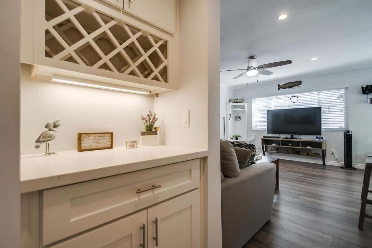 Una sala de estar moderna con un televisor de pantalla plana, un ventilador de techo y un comedor con mesa y sillas.