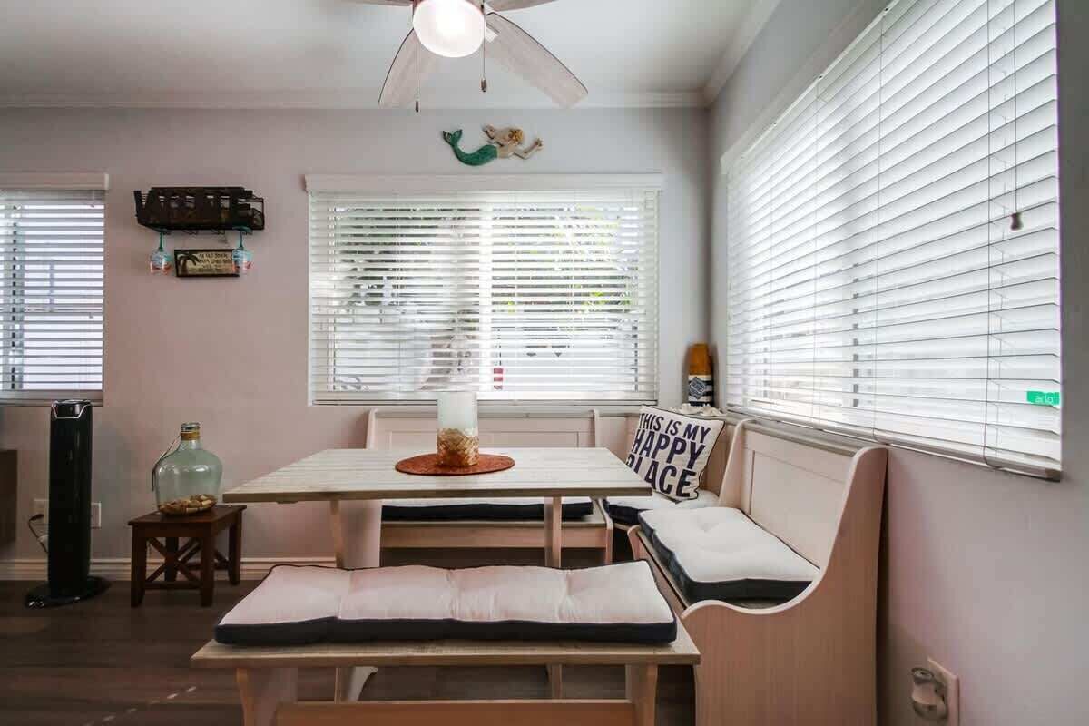 A dining area with a table, benches, and a ceiling fan.