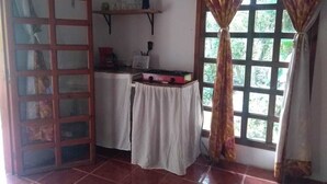 Een kamer met een betegelde vloer, een tafel met een wit tafelkleed, een rode doos en een raam met gordijnen.