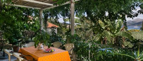 An outdoor patio with a table covered in an orange tablecloth, surrounded by wicker chairs.