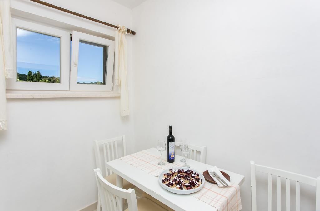 A dining table with a plate of food, a bottle of wine, and glasses.