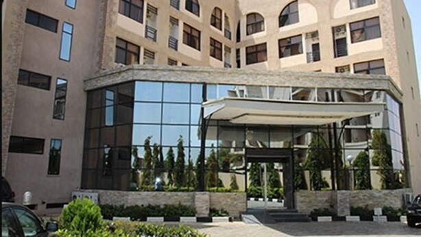 Un hotel de varios pisos con fachada moderna, ventanas grandes y una zona de acceso cubierta.