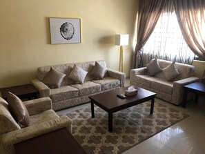 A living room with two sofas, a coffee table, and a lamp. - Stonehedge Hotels (Abuja)