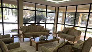 Una habitación amplia con ventanas grandes, muebles elegantes y una mesa de centro.