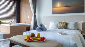 Une chambre d’hôtel avec un lit, un plateau de petit-déjeuner et un tableau représentant un coucher de soleil.