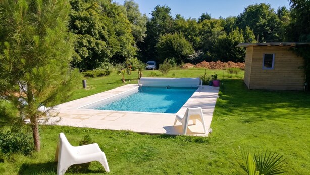A rectangular swimming pool with a tiled deck, surrounded by grass and trees. - Homerez - Villa in Château-la-Vallière. (Château-la-Vallière)