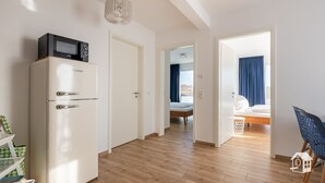 Un appartement moderne avec un réfrigérateur blanc, un lit doté de rideaux bleus et un plancher en bois.