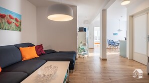 Una sala de estar moderna con un sofá oscuro, una mesa blanca y una lámpara colgante.