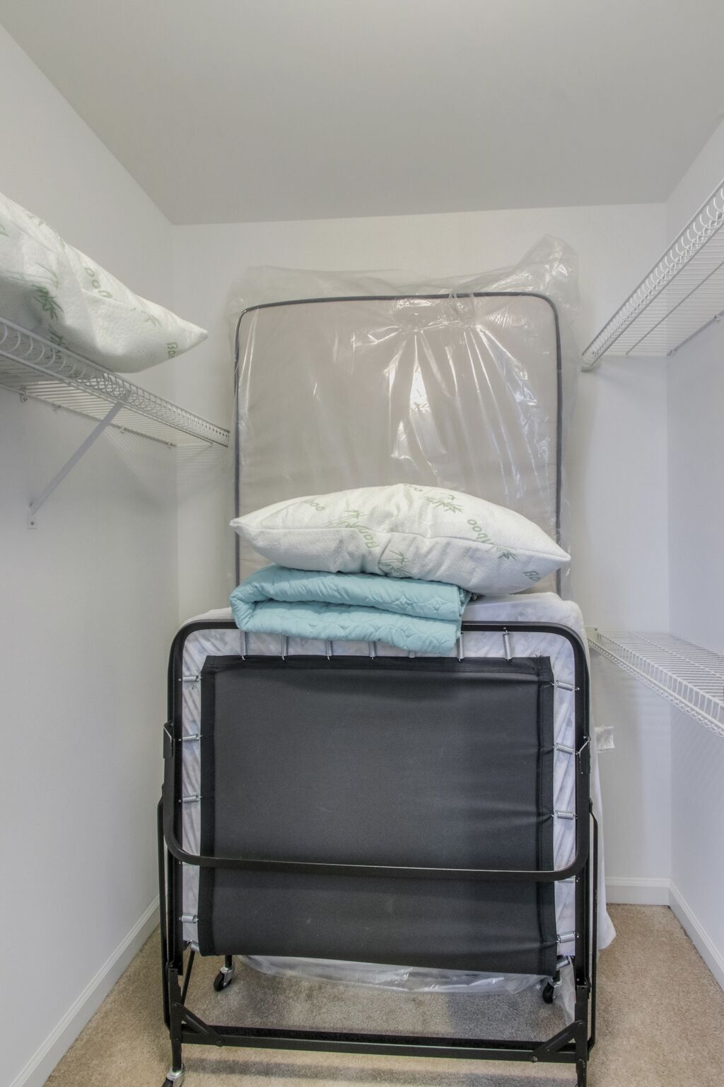 Una habitación pequeña con una cama, un estante en la pared y una bolsa de pl ástico.