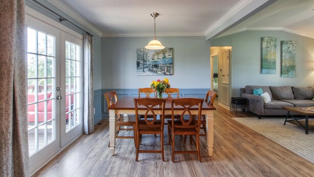 Een eetgedeelte met een houten tafel en stoelen, een kroonluchter en een schilderij aan de muur.