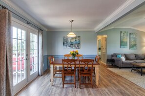 A dining area with a wooden table and chairs, a chandelier, and a painting on the wall. - A Hop, Skip and a Jump to it All! (Columbia)