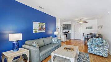 A living room with a blue wall, a grey sofa, a coffee table, and a patterned armchair.