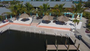 Een resort met een zwembad, rieten parasols en palmbomen.