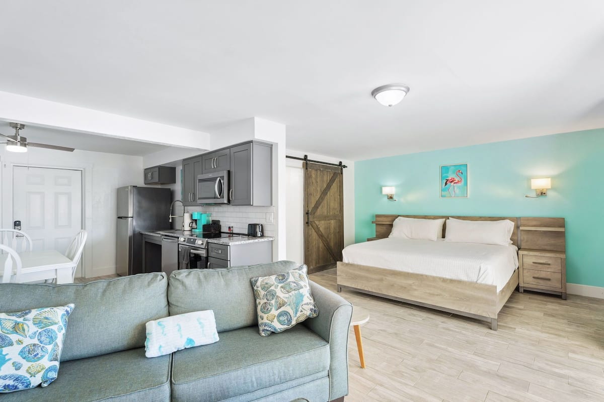 A compact bedroom with a bed, bedside tables, and a small kitchenette.