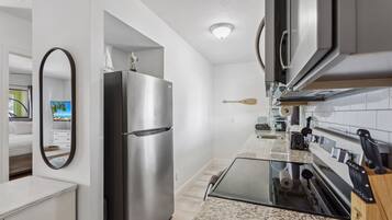 A modern kitchen with a stainless steel refrigerator, a glass-top island, and a built-in oven.