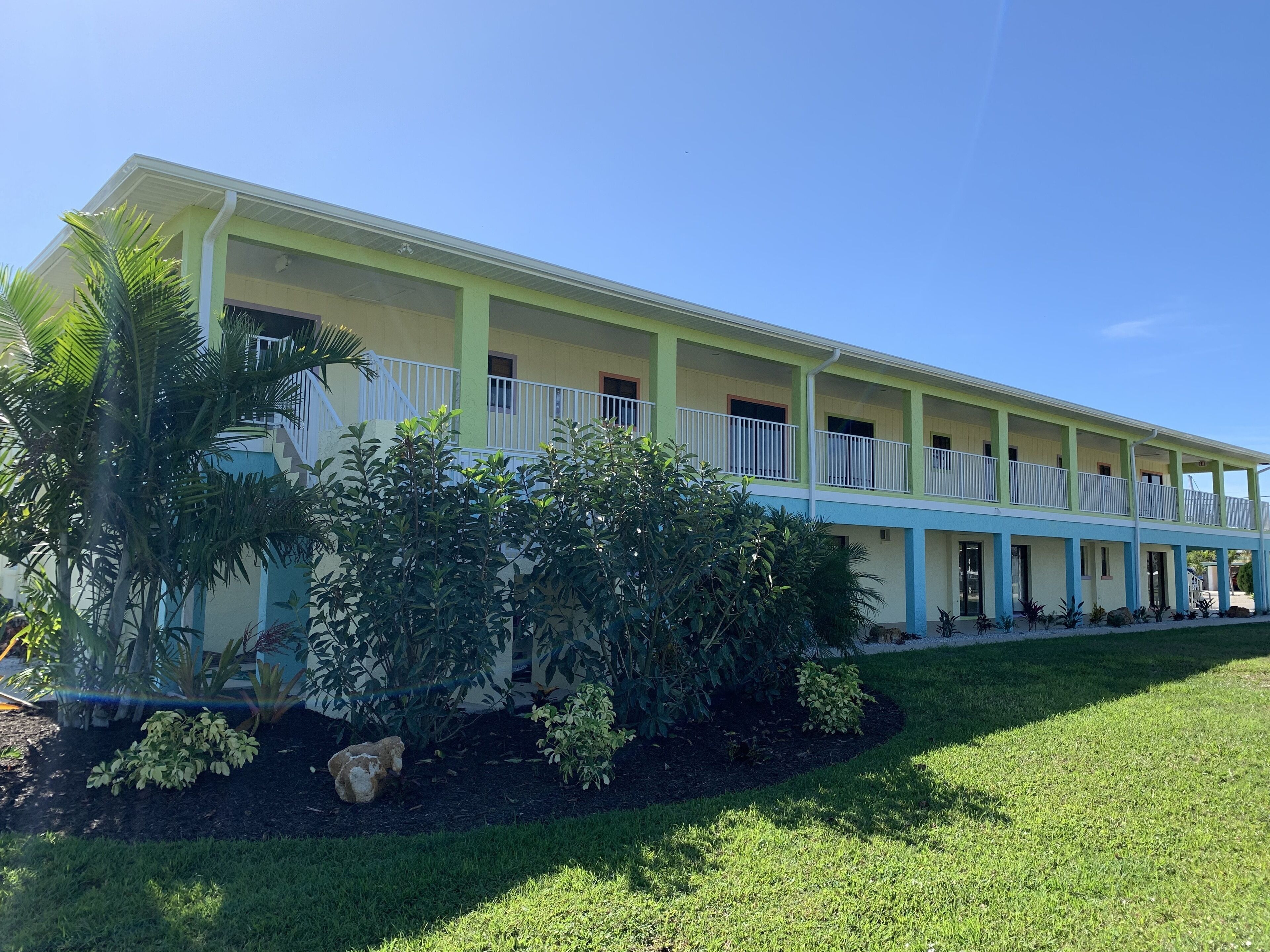A two-story building with a flat roof, multiple balconies, and a well-maintained lawn.