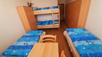 A dormitory room with bunk beds, a wooden table, and matching chairs.