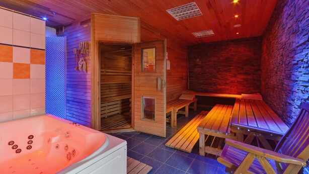 A sauna room with a wooden bench, a wooden table, and a hot tub. - Sporthotel BK Pod Lipou (Vedomice)