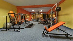 A gym with orange benches, weightlifting equipment, and a blue carpet. - Sporthotel BK Pod Lipou (Vedomice)