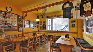 A restaurant with wooden tables and chairs, a large window, and various posters on the walls. - Sporthotel BK Pod Lipou (Vedomice)