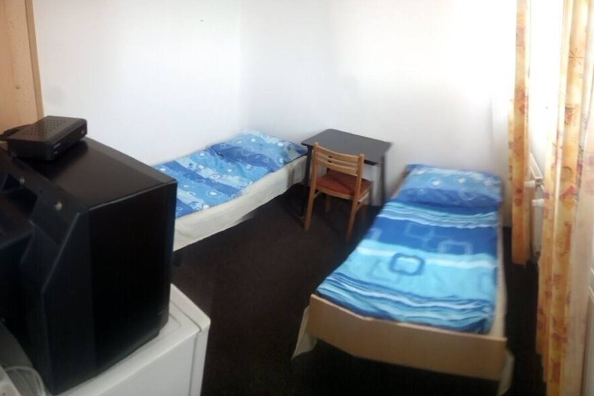 A small room with two single beds, a desk, and a chair.