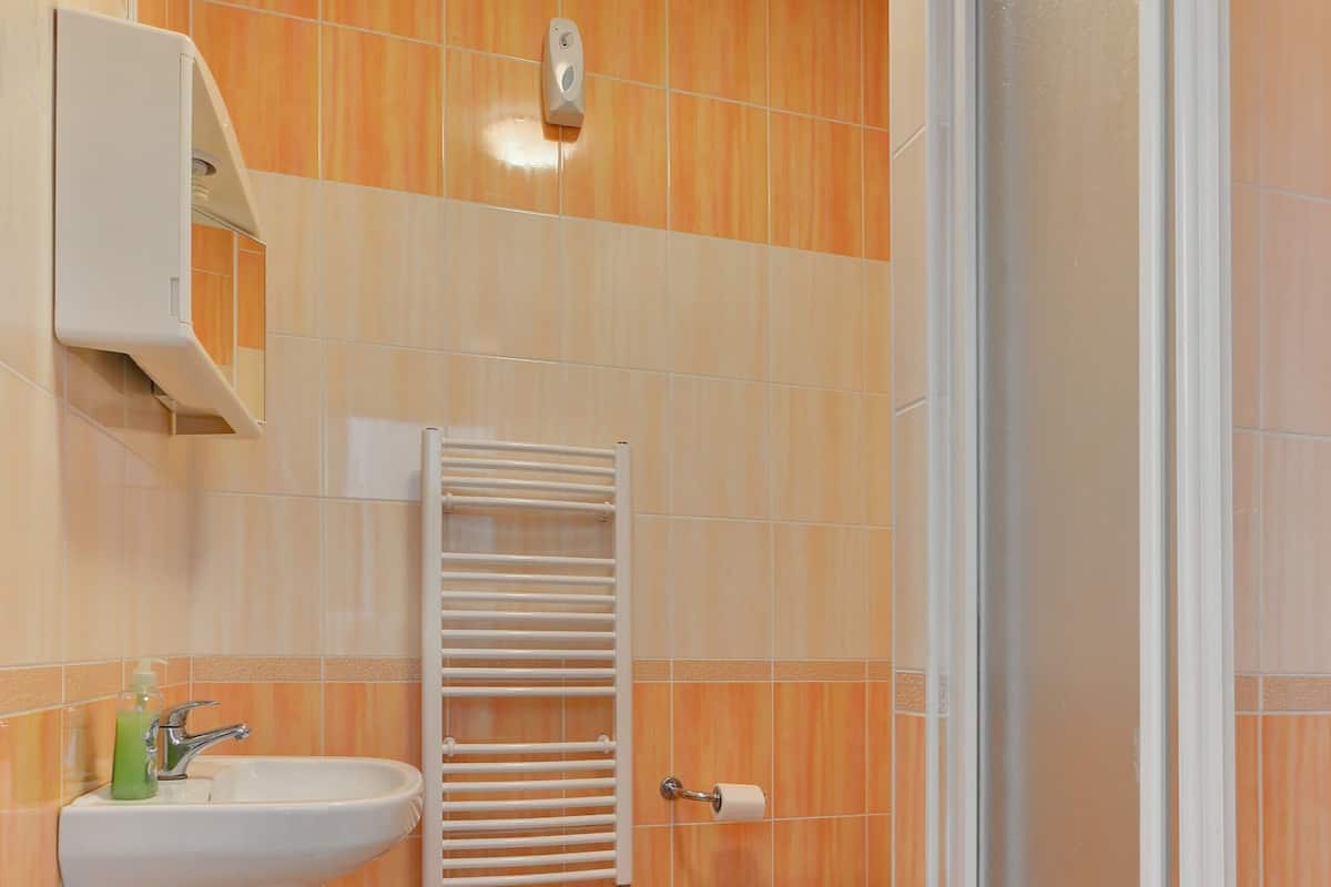 A bathroom with a sink, towel rack, and a shower area.