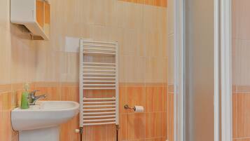 Un bagno con lavandino, porta asciugamani e zona doccia.