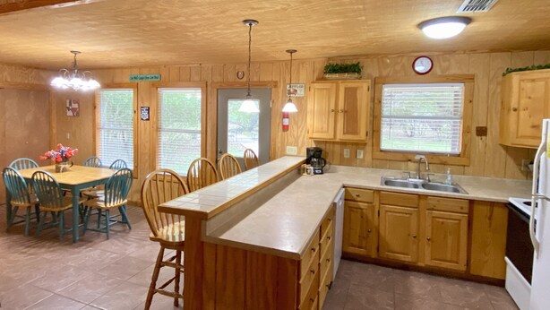 Una cocina de estilo cabaña de madera con comedor, armarios de madera, un lavamanos y un reloj en la pared.