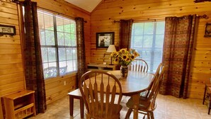 A wooden cabin dining room with a table, chairs, and a vase of sunflowers. - Float 2 Cabin ~ Private Frio River Access @ Comanche Crossing, Cowboy Style! (Concan)