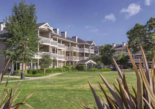 A multi-story hotel with balconies, a well-maintained lawn, and a gazebo.