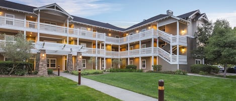 A multi-story hotel with a central courtyard, balconies, and a well-maintained lawn.