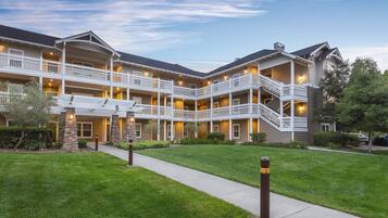 A multi-story hotel with a central courtyard, balconies, and a well-maintained lawn.