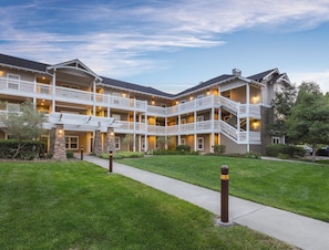 A multi-story hotel with a central courtyard, balconies, and a well-maintained lawn.
