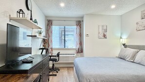 A bedroom with a bed, a desk with a chair, a television, and a window with curtains. - Beautiful & Cozy Studio Condo in Denver Tech Center (Greenwood Village)
