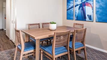 Un coin repas avec une table et des chaises en bois, une plante en pot et trois tableaux encadrés accrochés au mur.