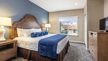 Une chambre d’hôtel comprenant un lit, deux lampes de chevet, une télévision, une fenêtre avec vue et une commode.