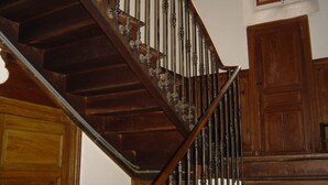 Eine Holztreppe mit aufwendiger Metallgeländer und einer Holztür am Fuß.