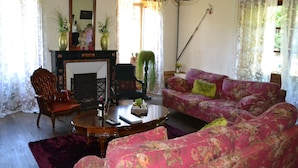 Ein Wohnzimmer mit Kamin, floralem Sofa und einer Chandelier.