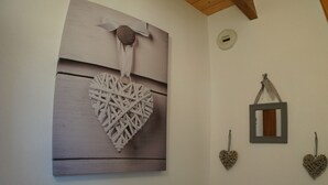 A bathroom with a white toilet, a wooden ceiling, and decorative heart-shaped wall hangings. - Seasonal rental apartment for up to 4 people (Bussang)