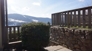 A stone wall with a wooden fence, a stone staircase, and a view of snow-covered mountains. - Seasonal rental apartment for up to 4 people (Bussang)