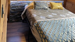 A cozy bedroom with a wooden headboard, a deer head decoration, and a bed with patterned bedding. - Seasonal rental apartment for up to 4 people (Bussang)