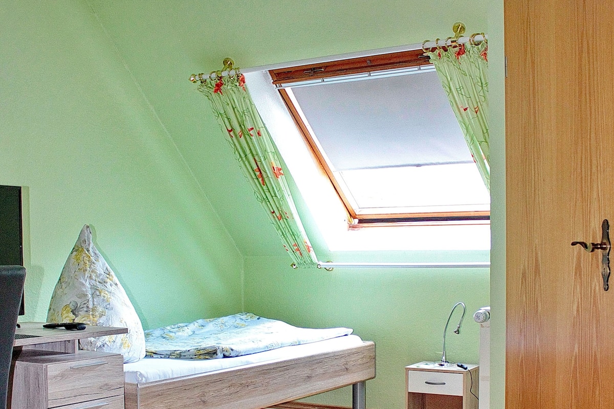 Une chambre avec un puits de lumière, un lit, un bureau et une armoire.