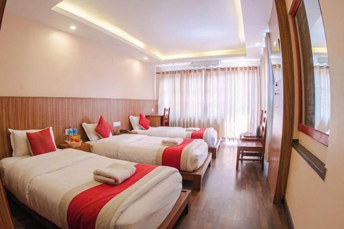 A hotel room with three beds, wooden headboards, and a wooden floor.