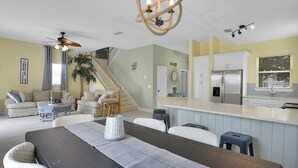 Amplia sala de estar con comedor, cocina y una escalera que lleva a un nivel superior.