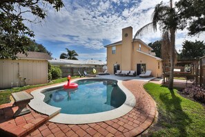 A backyard with a swimming pool, a brick patio, and a house with a yellow exterior. - Near the Mayo Clinic and 6 blocks from Ocean 3 bedrooms Pool Home (Jacksonville Beach)