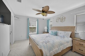 A bedroom with a bed, nightstands, a ceiling fan, and a wall-mounted TV. - Near the Mayo Clinic and 6 blocks from Ocean 3 bedrooms Pool Home (Jacksonville Beach)