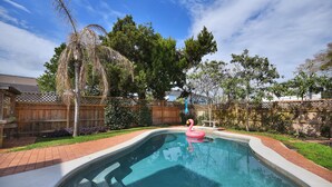 Un patio trasero con piscina, valla de madera y terraza de madera.